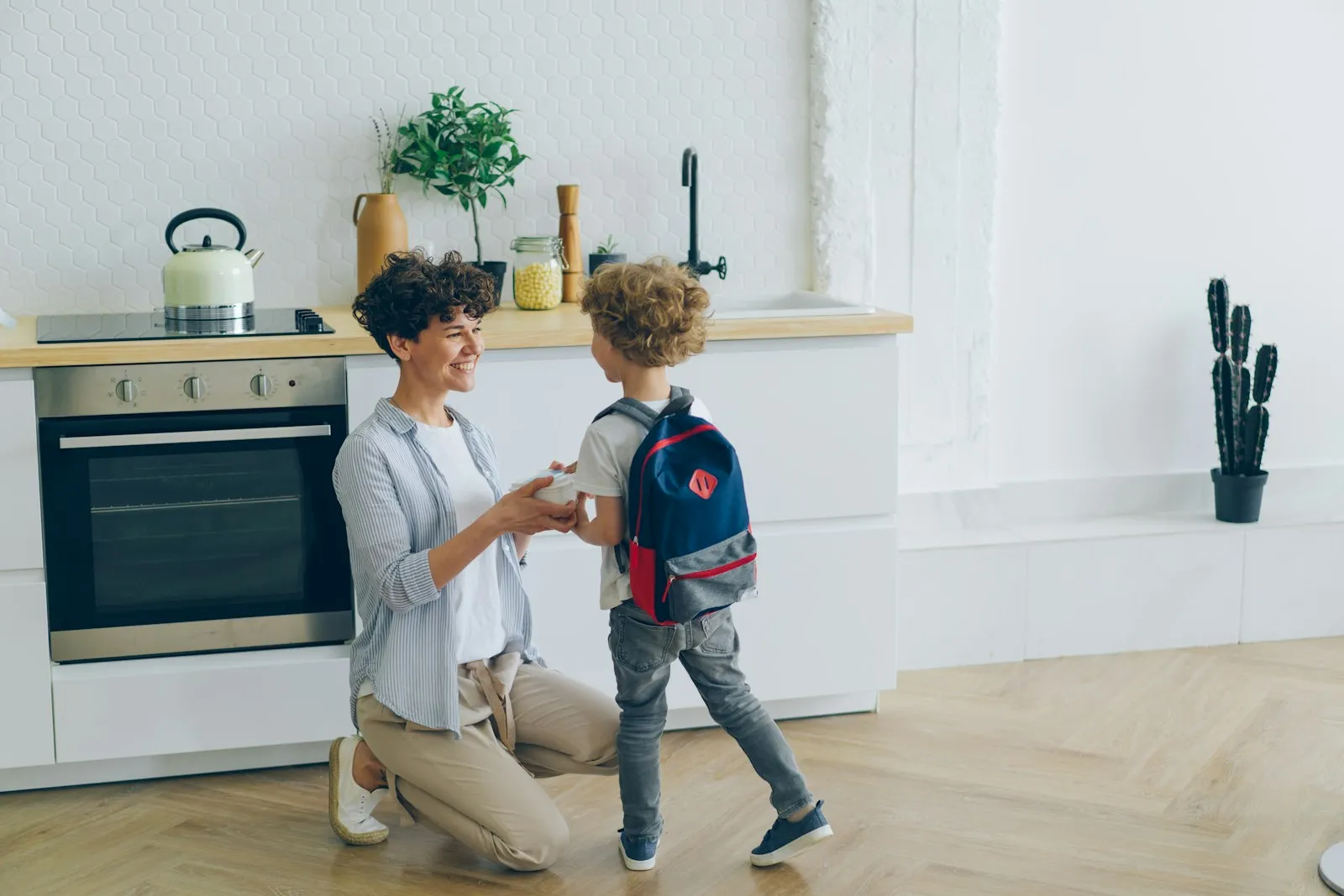 A mom helps her son with his backpack before school
